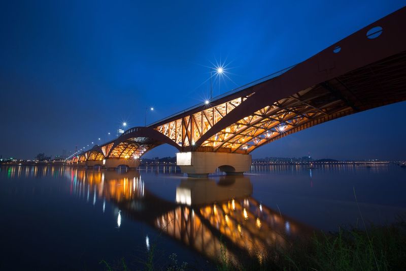 Illuminated seongsan bridge over han river against blue sky at night
