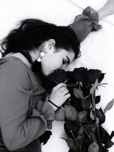 High angle view of teenage girl smelling rose on bed