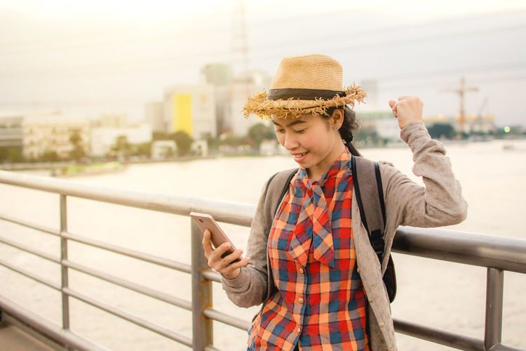 Young woman using mobile phone while standing on bridge