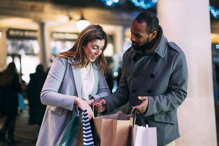 Woman discussing with man holding shopping bags at christmas market