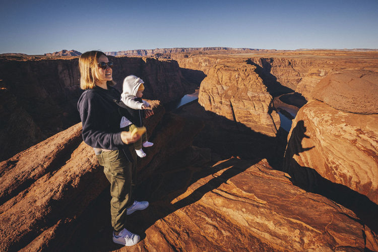 A woman with a child is standing near horseshoe bend, arizona