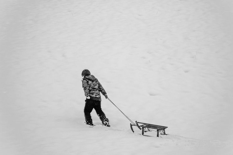 Boy pulling sled on snowy land
