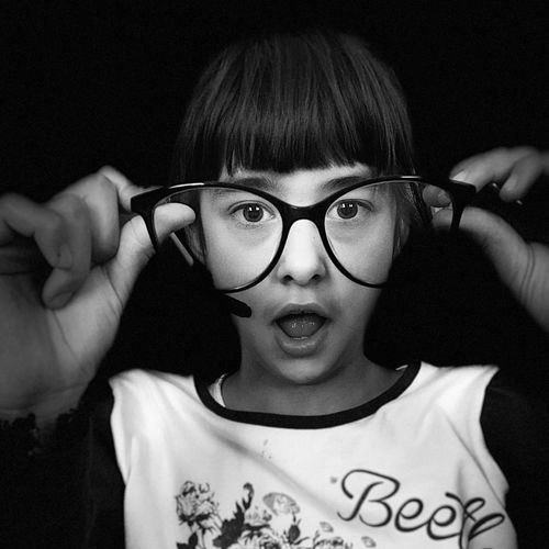 Portrait of girl wearing eyeglasses against black background