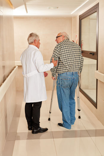 Rear view of doctor and patient standing in corridor