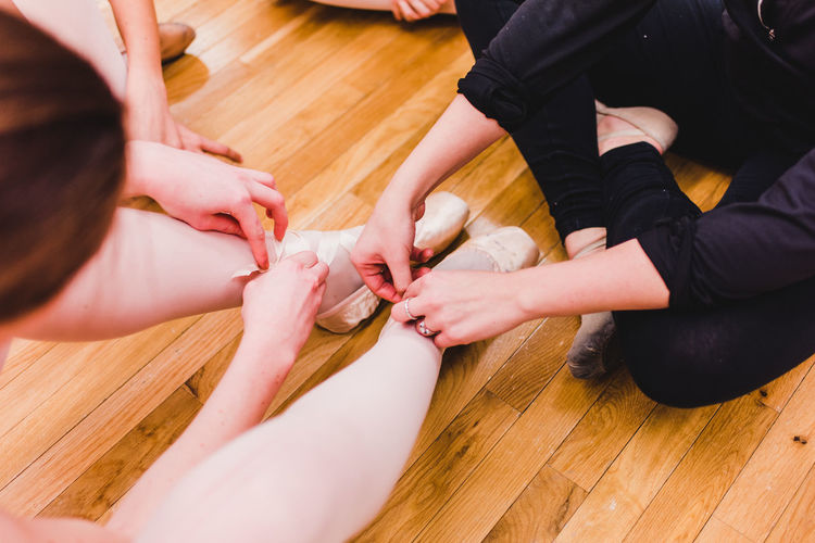 Low section of ballet dancers on hardwood floor