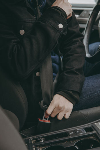Person fastening seat belt in car