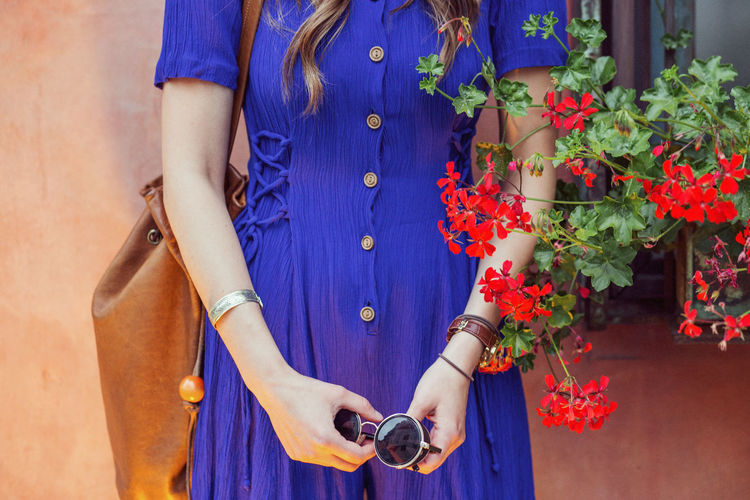 Detail of woman in blue dress holding sunglasses