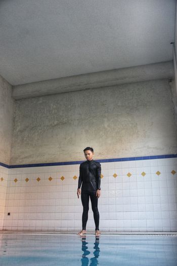Full length portrait of young man standing against wall