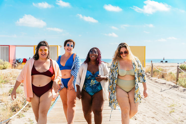 Friends in bikini standing at beach