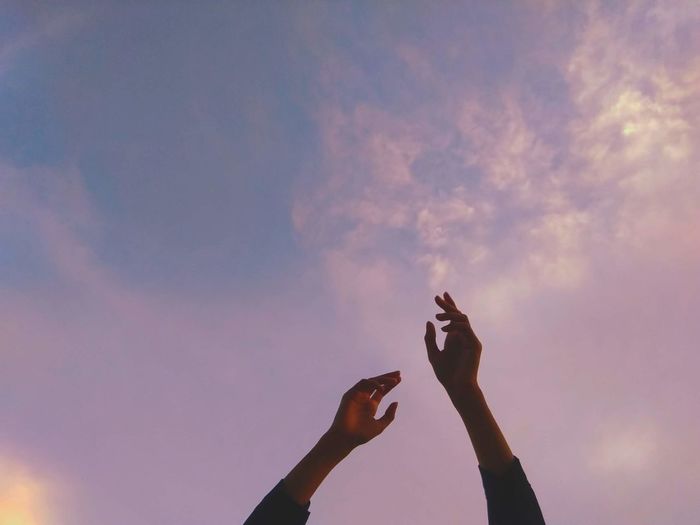 Two hands up in the pink sky