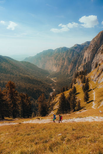 Rear view of people walking on field against mountain