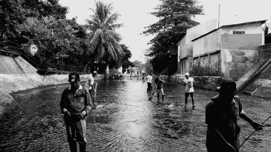 People walking on canal in city during rainy season
