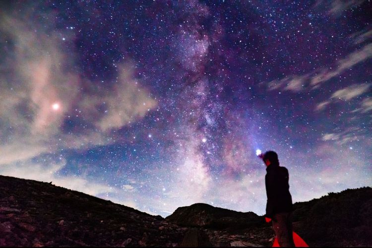 Side view of man standing against star field at night