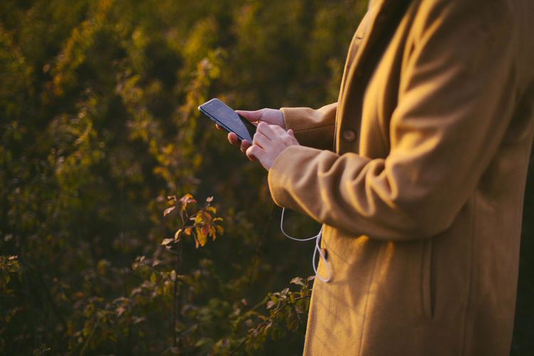 Midsection of woman using phone while standing outdoors