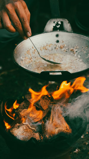 Close-up of hand holding pan while cook kerak telor