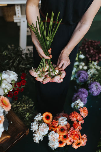 Midsection of woman holding bouquet in flower shop