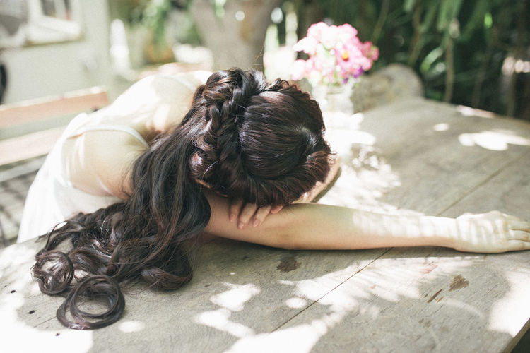 High angle view of sad woman resting on table in garden