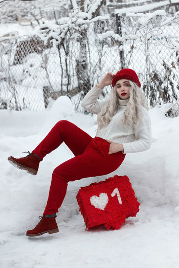 Young woman sitting on snow covered land
