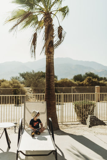 Young toddler boy with a mask on sitting by pool in palm springs