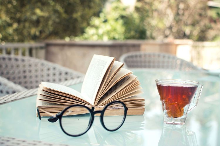 Close-up of glasses and an open book on table