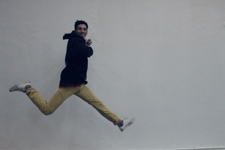 Full length of man jumping against wall