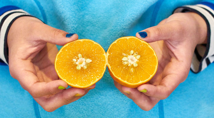 Close-up of hands holding halved orange