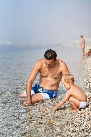 Rear view of shirtless man swimming in sea
