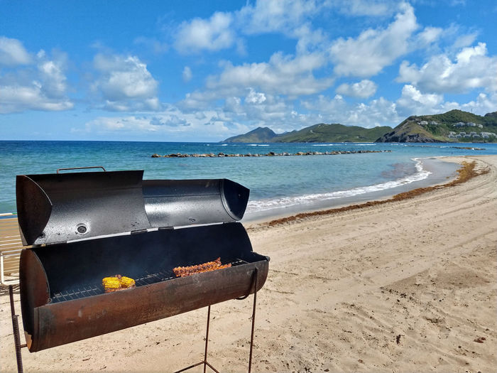 Scenic view of beach against sky with barbecue in foreground
