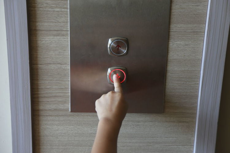 Cropped hand of girl pressing elevator button