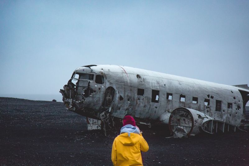 Rear view of woman standing on abandoned airplane