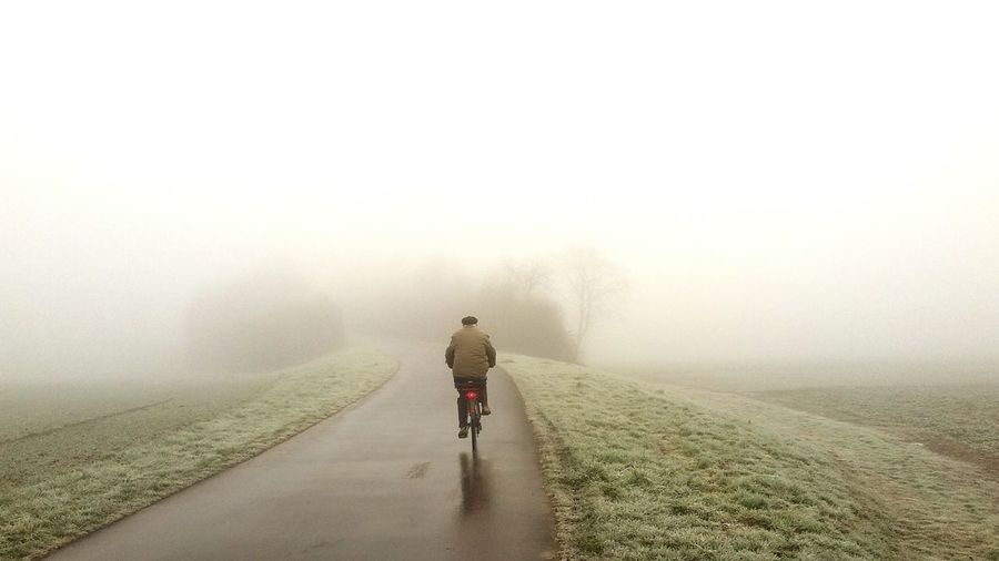 Rear view of two people walking on country road in foggy weather
