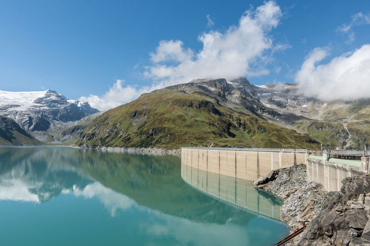 Scenic view of dam and mountains against sky