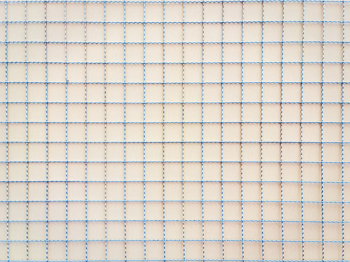 Full frame background of steel wire mesh against wooden wall