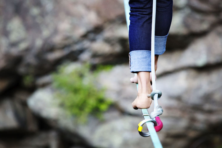 Low section of woman walking on rope against rocks