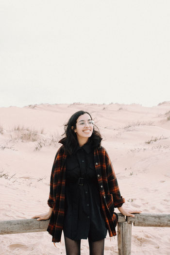 Portrait of young woman standing on sand at desert
