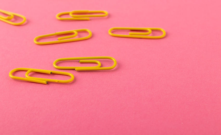 Directly above shot of paper clips over pink background