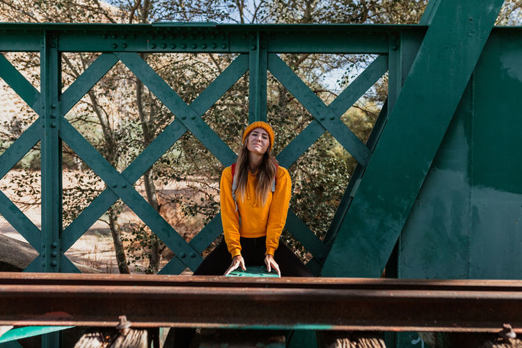 Portrait of young woman sitting on railway bridge