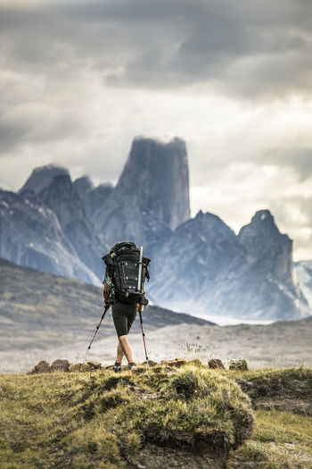 Backpacker hikes toward mount asgard in akshayak pass, baffin island