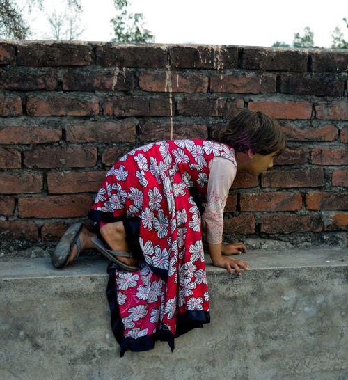 Girl kneeling on retaining wall
