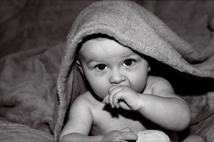 Close-up portrait of cute baby boy wrapped in towel at home
