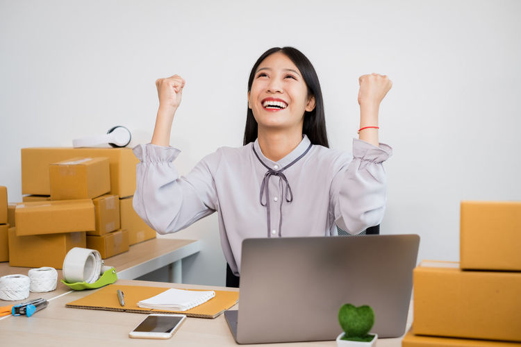 Cheerful woman celebrating while sitting at office