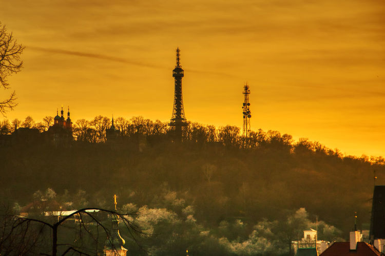 View of communications tower and buildings against sky during sunset