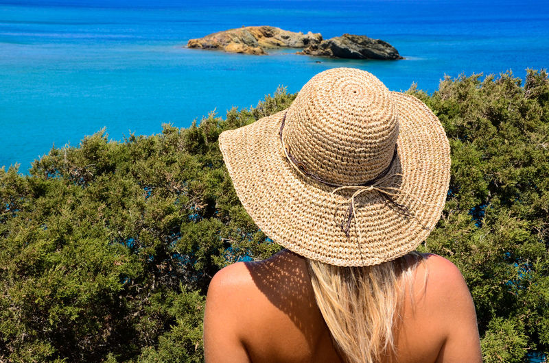 Rear view of young woman wearing hat looking at the sea