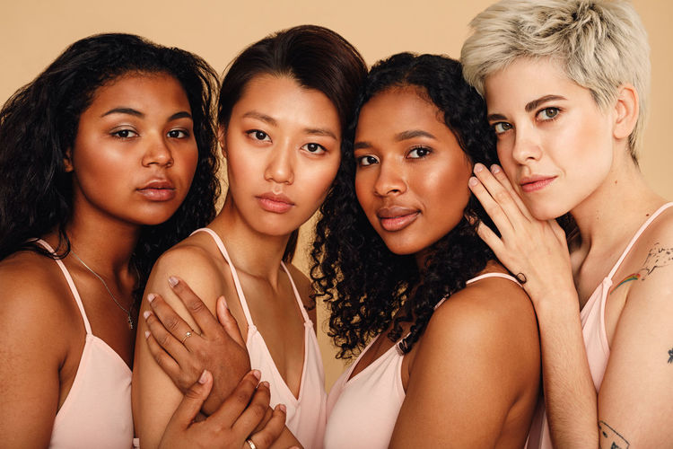 Portrait of friends standing against beige background