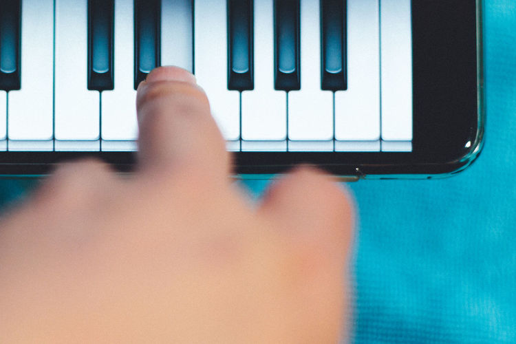 Cropped hand of person playing piano in mobile phone