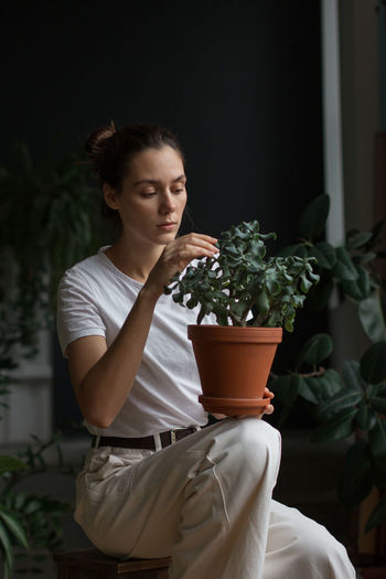 Young woman sitting on potted plant