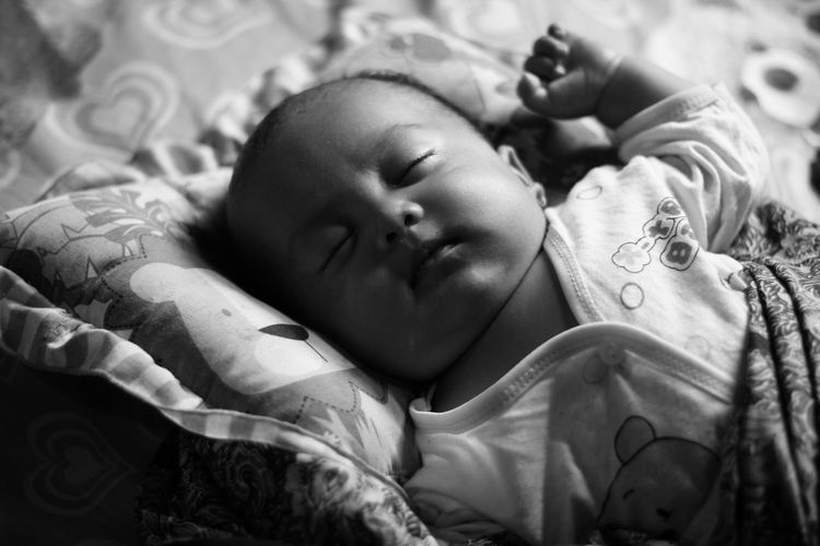 Close-up of baby girl sleeping on bed at home