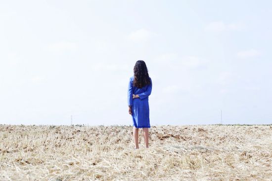 Rear view of woman standing on field against sky