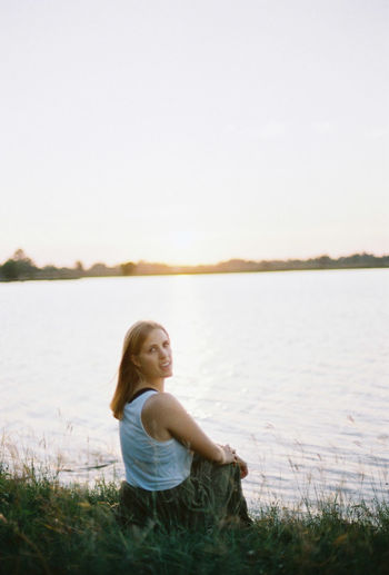 Woman sitting in lake against sky