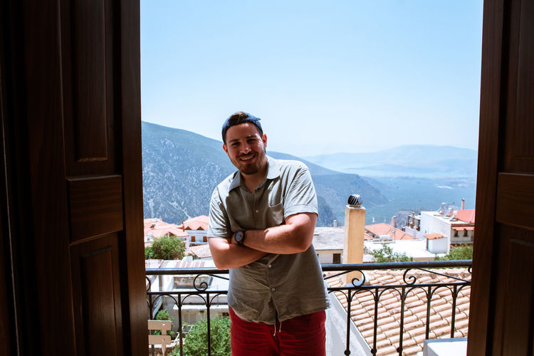 A young man with a beard in a balcony near the mountains